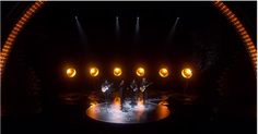 a group of people standing on top of a stage in front of bright yellow lights