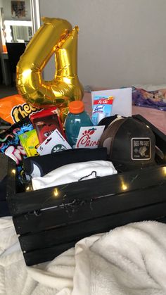 an open suitcase filled with items on top of a white bed next to a gold number 40 balloon