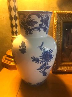 a blue and white vase sitting on top of a wooden table next to a painting