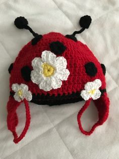 a crocheted ladybug hat with white and black flowers on the front