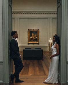 a man and woman standing in an art museum looking at each other