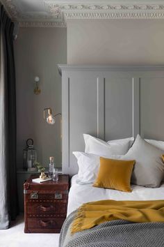 a bed with white sheets and yellow pillows