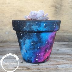 a painted flower pot sitting on top of a wooden table