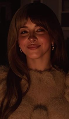 a woman with long hair smiling at the camera in front of a lit up candle