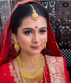 a woman wearing a red and gold bridal outfit, with her nose ring in the middle