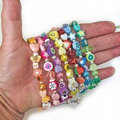 a hand holding a bunch of colorful bracelets on it's palm with an embellishment in the middle