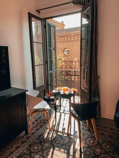 an open door leading to a balcony with chairs and tables in front of the window