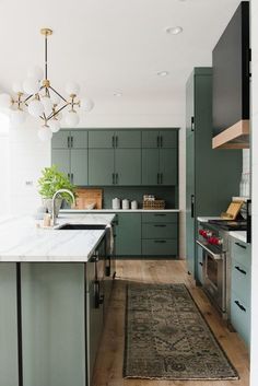 a kitchen with green cabinets and an area rug on the floor in front of it