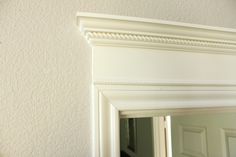 a bathroom mirror sitting above a sink under a faucet mounted on a wall