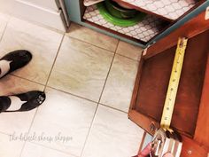 a person standing on the floor holding a pair of scissors in front of a drawer