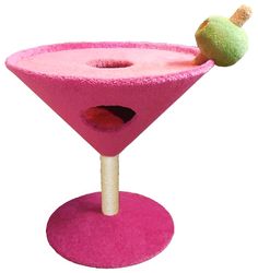 a pink cocktail glass with a green apple on the top and a wooden stick sticking out of it