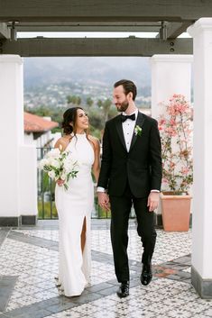 a bride and groom walking through an archway