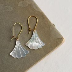 These beautiful Art Deco earrings are pure Mother of Pearl which has been carved into a simple scalloped fan shape.  The pearl has an incredible sheen and take on a subtle glow when they catch the light.  They are finished with gold plated earwires and are designed to hang just below the earlobe.  The length of the earrings is around 45mm (just under two inches).  🖤 FASTER SHIPPING 🖤Need this fast? We offer a Faster Shipping option here:https://www.etsy.com/uk/listing/100107311/faster-shipping Gold Art Deco Earrings, Metal Jewelry Making, Art Nouveau Earring, Silk Purse, Wedding Day Jewelry, Mother Of Pearl Jewelry, Deco Earrings, Mother Of Pearl Earrings, Fan Earrings