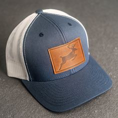 Stylish leather patch hats with Deer Stamp, personalization, or logo! SPECS *Leather Patch Color Options: Natural Dublin, Nut Brown Dublin, or Cafe Chromexcel *Hat Color Options: Choose from Navy/White, Charcoal, or Green/Khaki *All of our products are made to order by hand in McKinney, TX MATERIALS *REAL HORWEEN LEATHER: Premium Full-Grain Leather. oEach patch is one-of-a-kind and made from part of a whole hide of leather. There will be unique variation from item to item that truly makes it you Deer Stamp, Hunting Apparel, Patch Hats, Personalized Hats, Horween Leather, Company Gifts, Hat Ideas, White Charcoal, Hunting Clothes