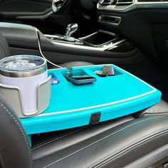 a blue tray with a cup and cell phone on it in the passenger seat of a car