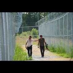 two men walking down a dirt road next to a fence with the words, you're family too