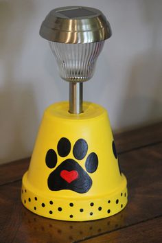 a yellow dog bell with a paw print on it's side and a metal base