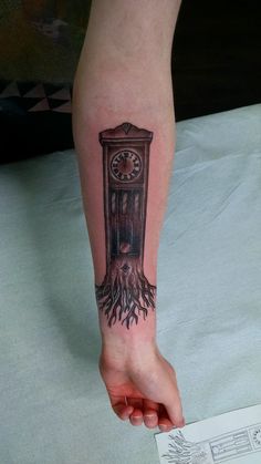 a person's arm with a clock and tree tattoo on it