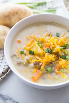 a white bowl filled with soup next to potatoes