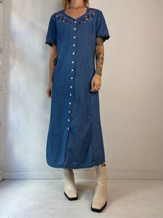 "- Vintage Wardrobe Essentials button up denim dress - Floral embroidery details - Ruffle trim on the sleeves - 100% cotton - Made in China - Tagged 12   Bust: 20.5\" Waist: 19\" Length: 49\"" Cotton Denim Midi Dress With Buttons, Cotton Denim Midi Dress With Button Closure, Cotton Midi Denim Dress With Button Closure, Elegant Ribbed Collar Top, Denim Blue Cotton Dress With Buttons, Button-up Denim Blue Cotton Dress, Denim Blue Cotton Button-up Dress, Denim Blue Relaxed Fit Denim Dress With Button Closure, Blue Cotton Denim Dress With Buttons