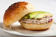 a sandwich with meat and avocado on a white plate, ready to be eaten