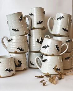 a stack of coffee mugs with bats painted on them