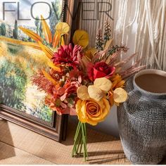 a vase with flowers sitting next to a painting