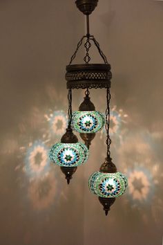 three lights hanging from a chandelier in front of a sky filled with clouds