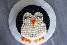 a cake made to look like a penguin on a white plate with black and orange icing