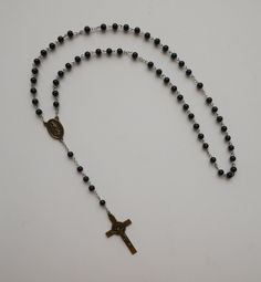 "This beautiful Lady of Guadalupe ROSARY with St Benedict 2\" Brass Crucifix is made at our shop in Miami. The Saint Benedict 2\" Crucifix is made in Italy. PLEASE NOTE THAT THIS ROSARY IS NOT INTENDED TO BE USED AS A NECKLACE ROSARY AND WE DON'T RECOMMEND TO USE IT AS SUCH. SIZE/LENGTH:  16\" long including the Crucifix (circumference is 23\"). BEADS: Made with 5 mm round glass beads.  CRUCIFIX: Brass Tone Saint Benedict Crucifix 2\" L x 1-3/16\" W. CENTER PIECE: Guadalupe brass center piece me Black Rosary, St Benedict, Saint Benedict, Lady Of Guadalupe, Beautiful Lady, The Saint, Prayer Beads, Black Glass, Rosary