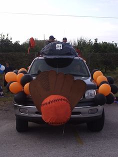 a truck with an orange ball and baseball on the back is parked in a parking lot