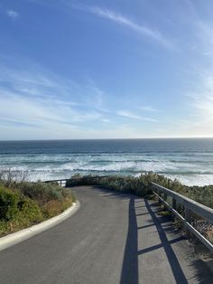 an empty road next to the ocean on a sunny day