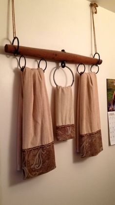 three towels hanging from hooks on a wall next to a calendar and postcard with an image of a horse in the background