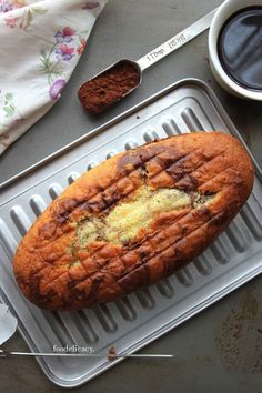 a loaf of cake sitting on top of a pan next to a cup of coffee