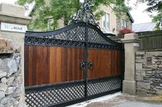 an iron and wood gate with stone walls