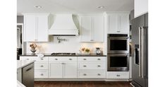 a kitchen with white cabinets and stainless steel appliances in the center, along with wood flooring