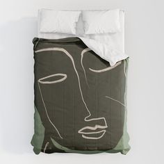 a bed covered in a green and white comforter with a drawing of a woman's face on it