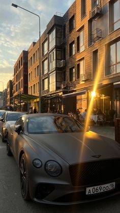 several cars parked on the street in front of apartment buildings at sunset or sunrise time