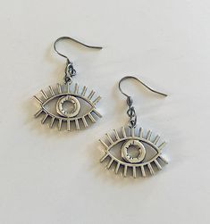 Evil eye earrings, silver eye earrings, ancient Egyptian/ Greek protection from the evil eye earrings, detailed eye charms. STAINLESS STEEL ear wires fish hooks jewelry. Egypt god Horus, for that witchy woman, Wicca Wiccan Witch. Occult esoteric occultism *earring wires measure approx .6 of an inch, or just over half an inch *charm itself approx .8 of an inch, (or just over half an inch) *STAINLESS STEEL earring wires fish hooks *charms are silver alloy *comes in a gift box earrings eye evileye Metal Dangle Earrings With Evil Eye, Symbolic Eye-shaped Silver Jewelry, Silver Metal Evil Eye Jewelry, Silver Metal Jewelry With Evil Eye, Evil Eye Symbolic Metal Jewelry, Symbolic Evil Eye Metal Jewelry, Fish Hook Jewelry, God Horus, Wiccan Witch