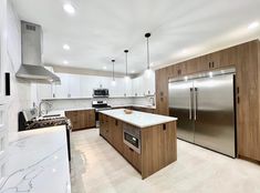 a large kitchen with an island and stainless steel refrigerator