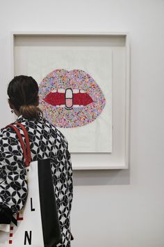 a woman is looking at an art work on display in a room with white walls