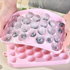 a person holding an ice tray filled with balls