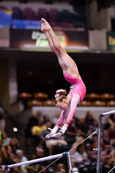 a woman is performing on the bars in front of an audience