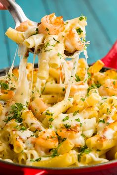 a fork full of pasta with shrimp and parmesan cheese being lifted from the skillet