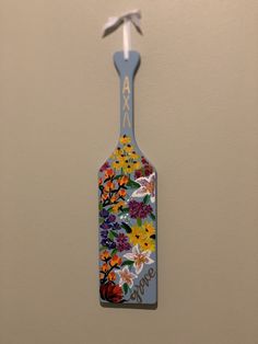 a flowered bottle hanging from the side of a wall with an arrow on it