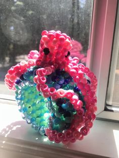 a vase sitting on top of a window sill filled with lots of colorful beads