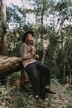 a woman sitting on a log in the woods