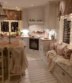 a kitchen filled with lots of white furniture and lights on the windows sills