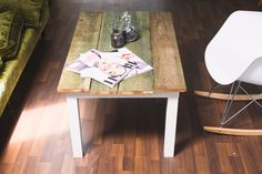 a wooden table with magazines on it next to a white rocking chair