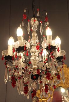 a chandelier hanging from the ceiling with red and clear glass beads on it